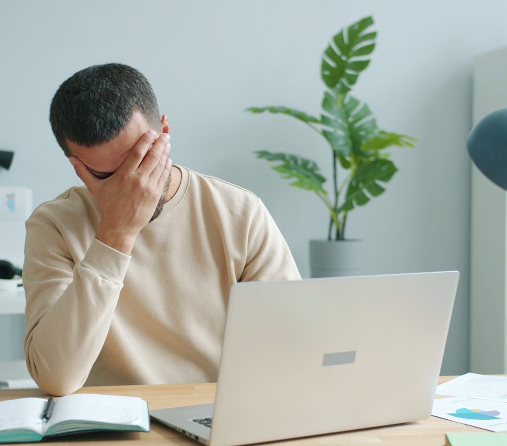 Man rubbing his face in front of laptop
